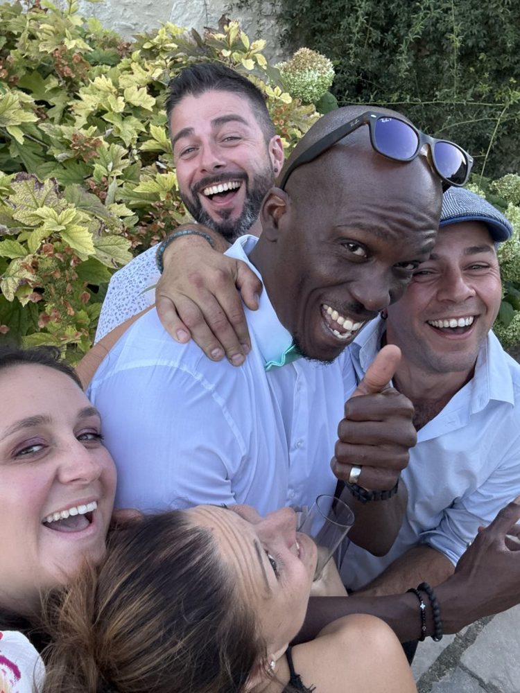 Des invités d'un mariage, hilares, serrés dans un câlin de groupe